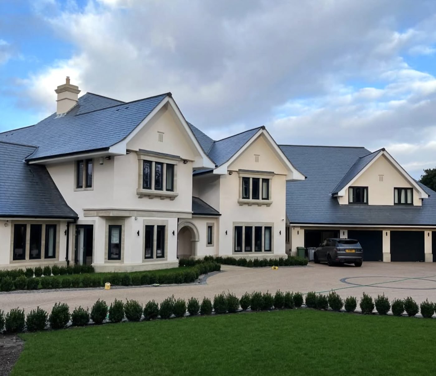 Large detached house in cream render with a long gravel drive