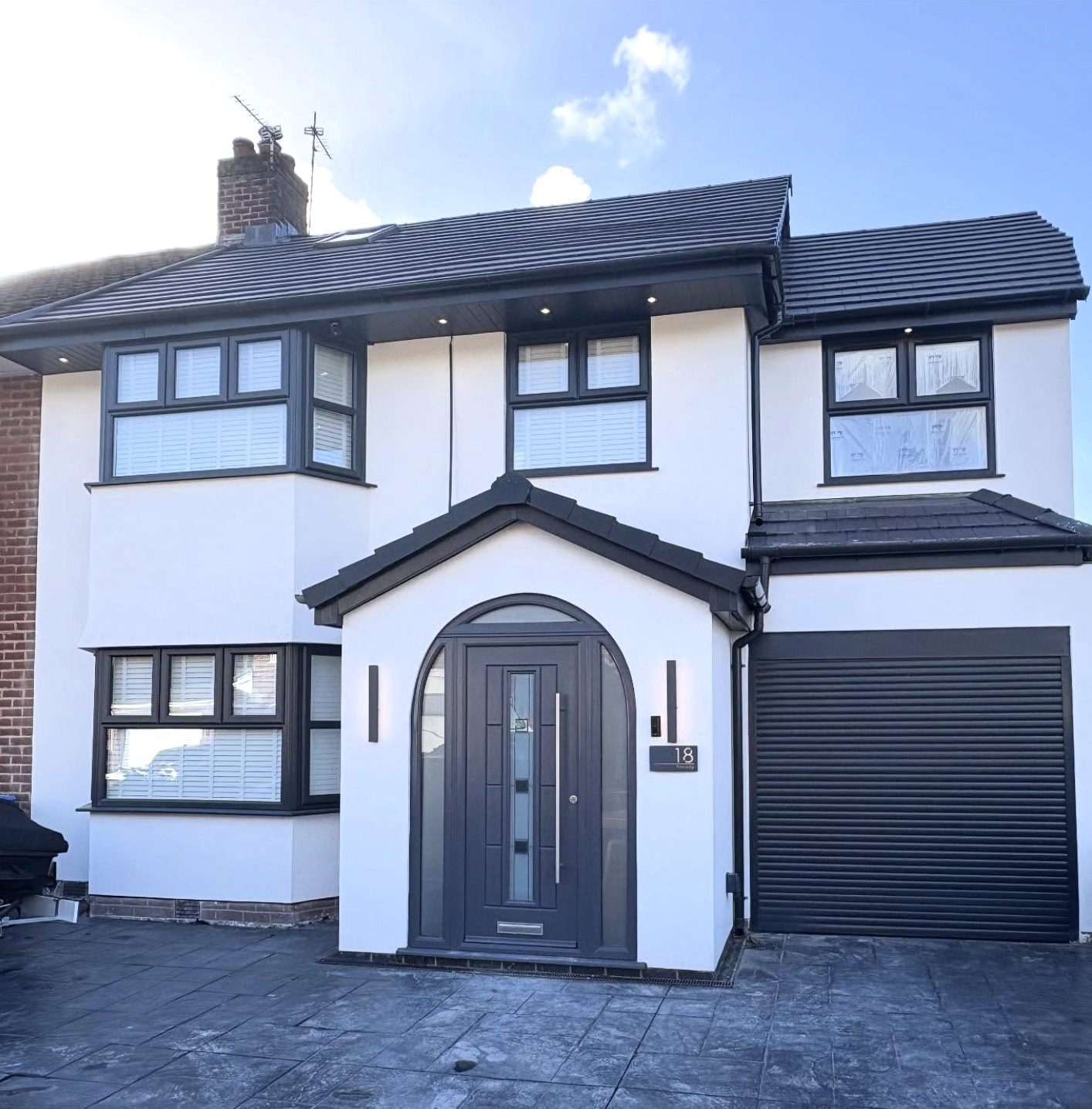 Semi-detached house in white render with an arched entrance and a garage