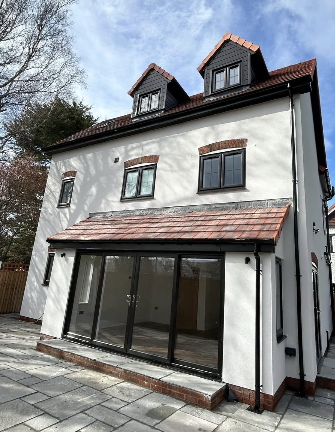Three-storey back wall in white render with dormers and a tiled single-storey extension