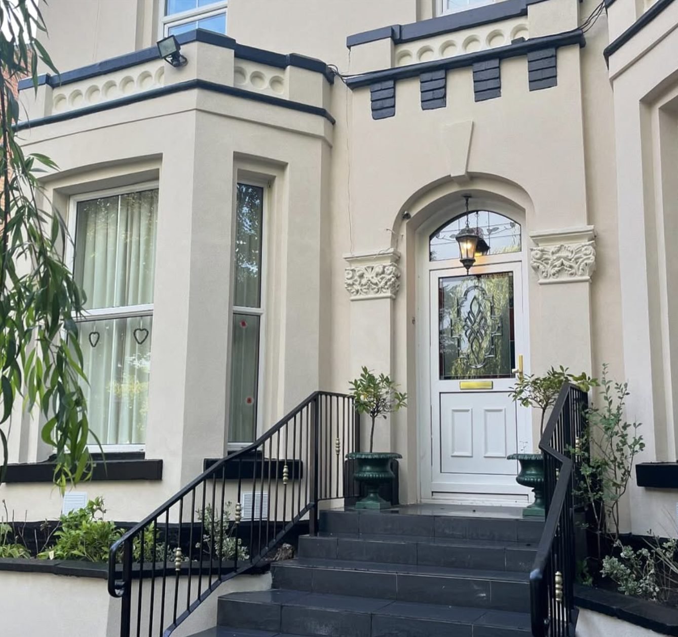 Victorian front with a cream rendered bay, decorative door surround and black railings