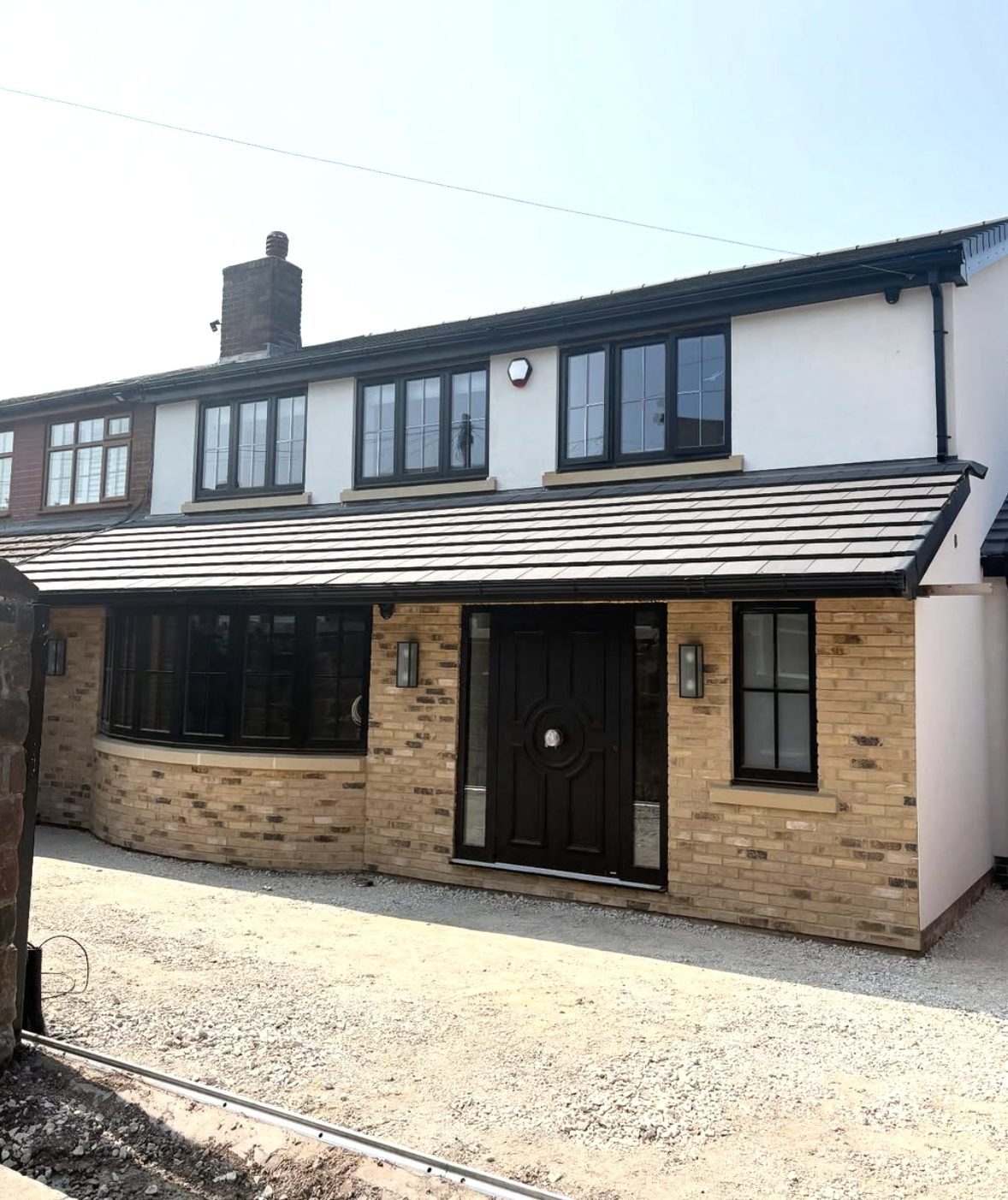 House with white render above a new buff brick front extension