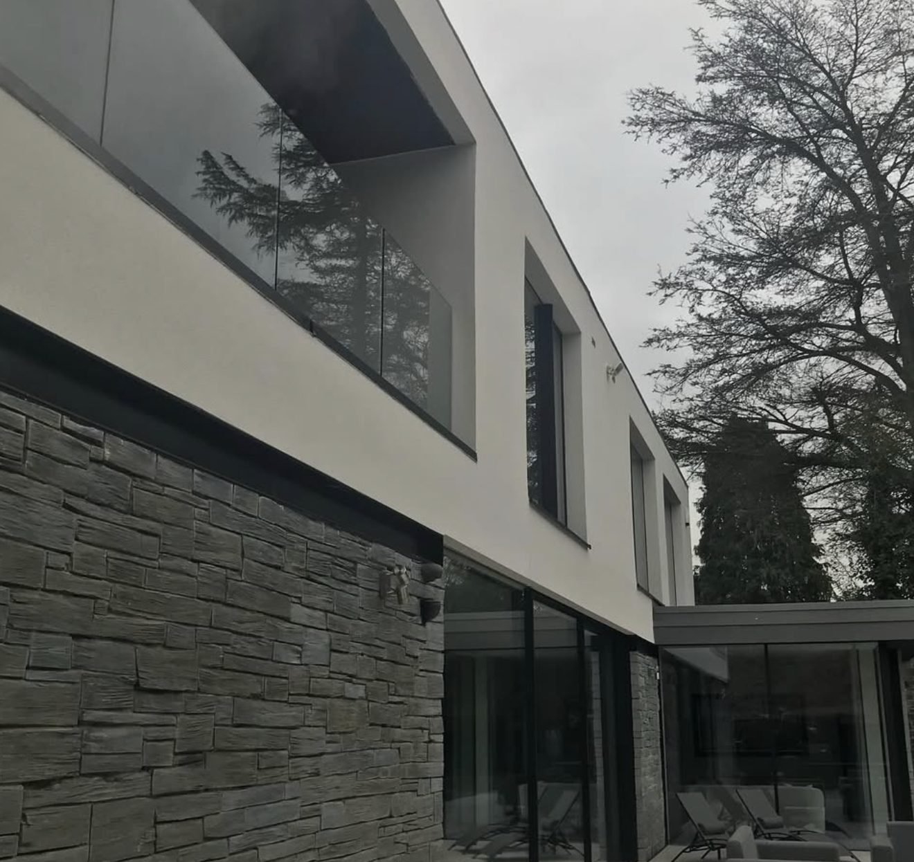 Modern house with a white rendered upper floor over dark stone cladding